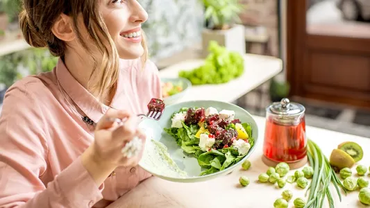 Donna che si gode un piatto di frutta fresca in relax, esempio di pasto per una ricetta estiva e proteica.