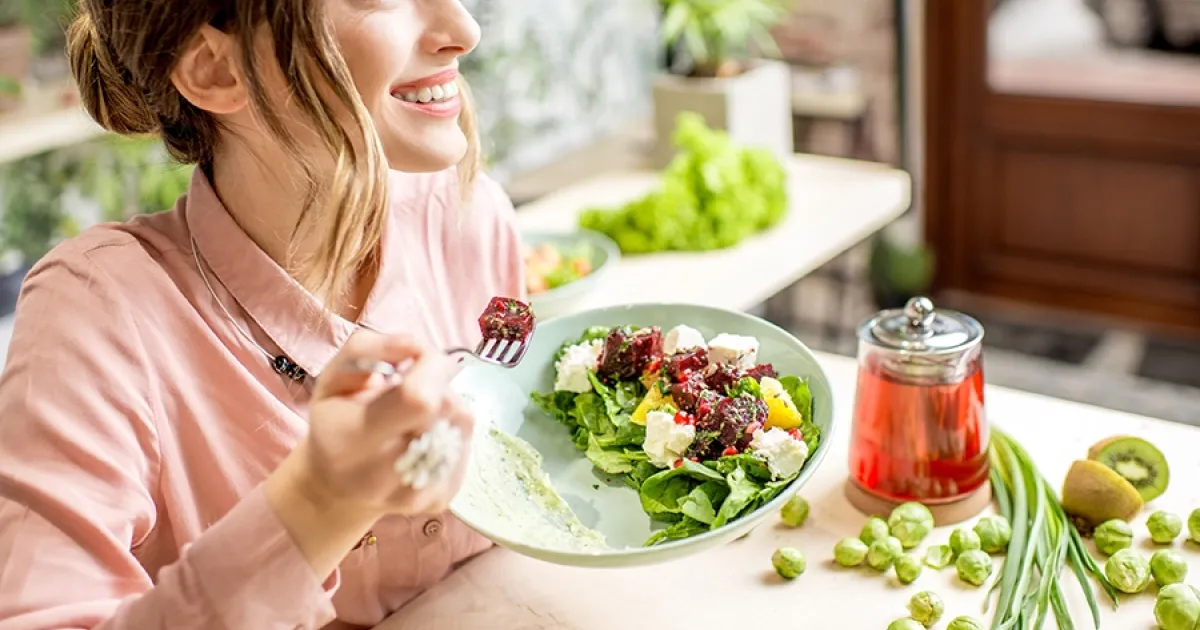 Donna che si gode un piatto di frutta fresca in relax, esempio di pasto per una ricetta estiva e proteica.