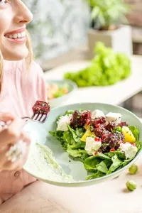 Donna che si gode un piatto di frutta fresca in relax, esempio di pasto per una ricetta estiva e proteica.